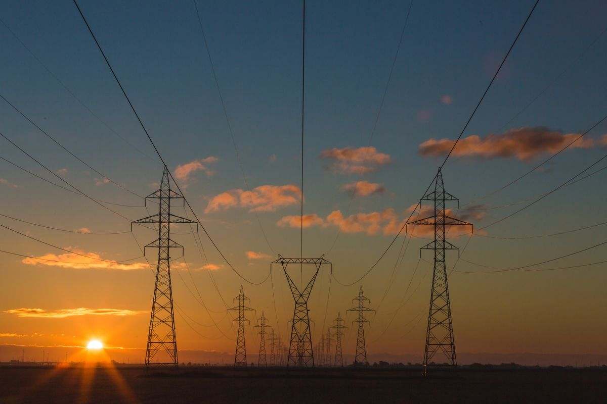 High-voltage power transmission towers at sunset — representing Alberta's abundant power infrastructure for data center development